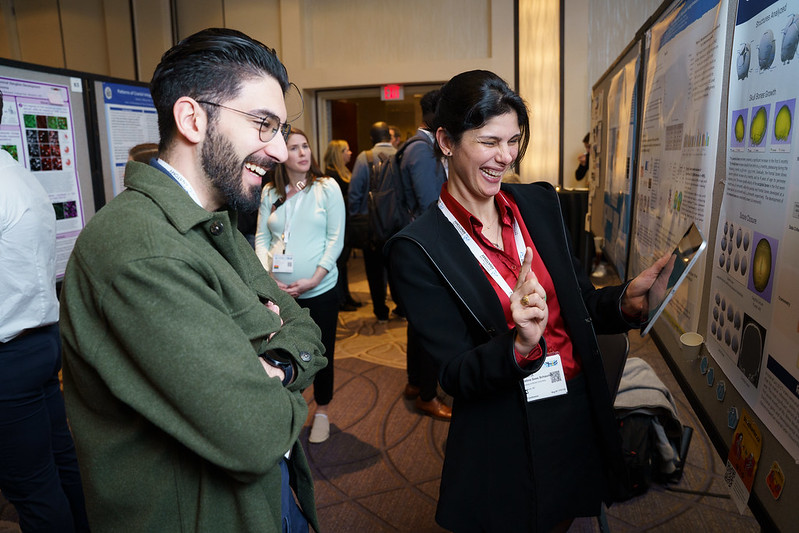 two people conversing and laughing while taking in a poster presentation